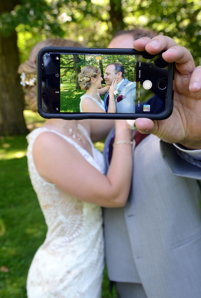 Fun wedding photo of the bride and groom with cell phone by Columbia Photos. Columbia Photos is wedding photography based in London Ontario.